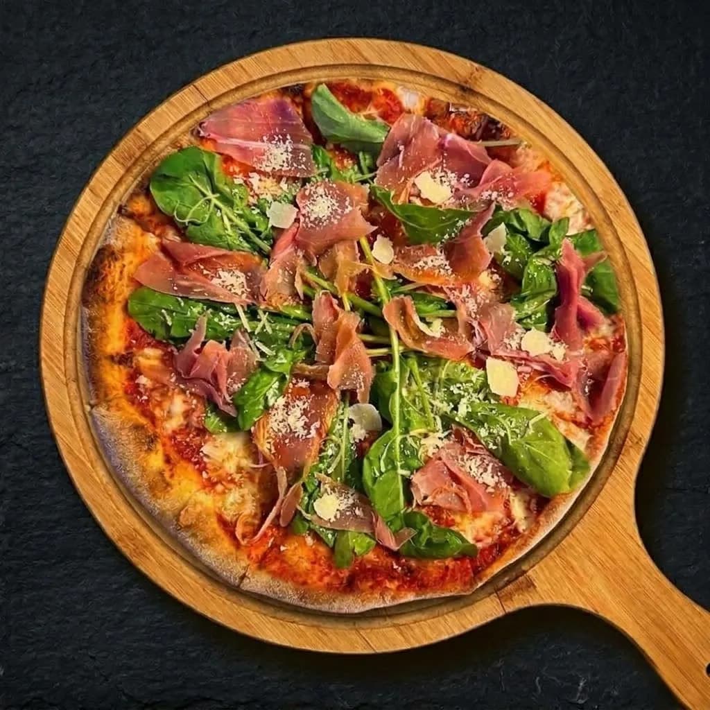 Parma Ham pizza with rocket and parmesan on a wooden board